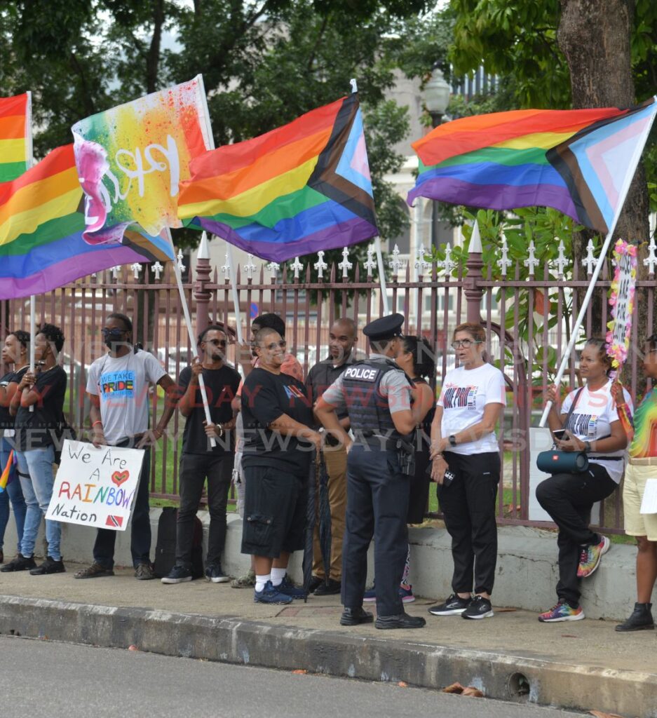 A police officer speak with members of PrideTT staged their annual parliament demonstration outside the Red House, Abercromby Street, Port of Spain on Friday. - Photo by Anisto Alves