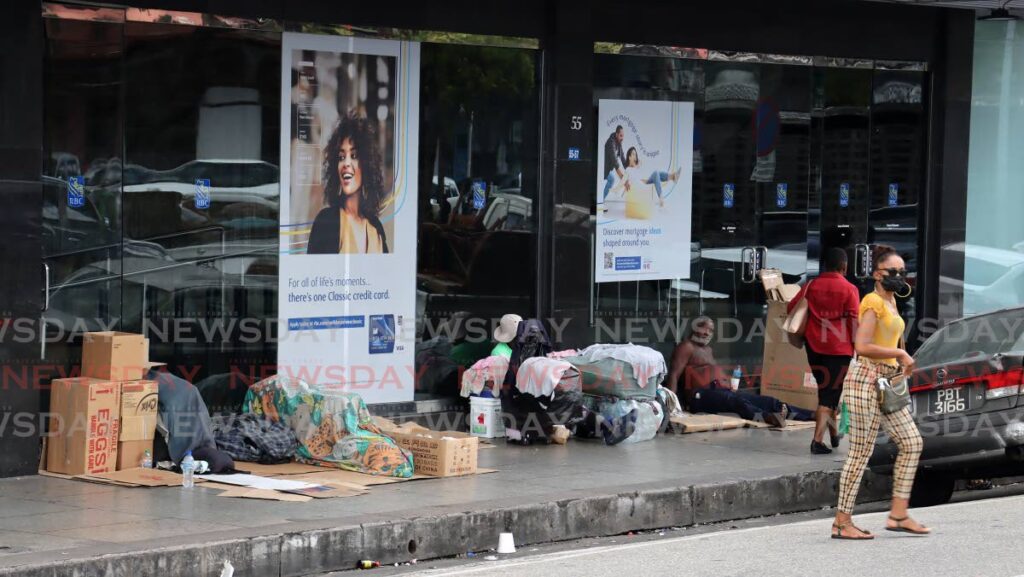 Homeless people lie on the pavement outside a commercial bank in Port of Spain. - ROGER JACOB