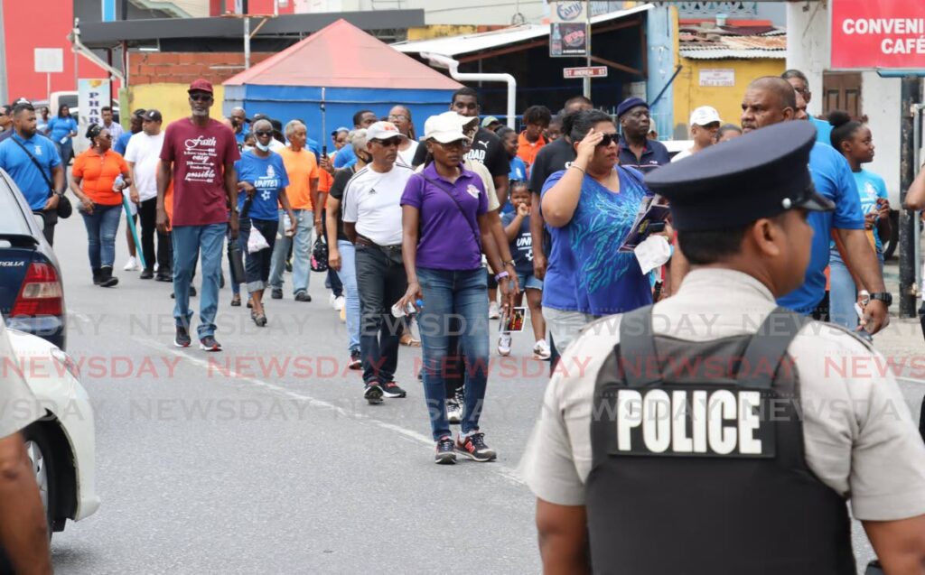 Couva residents and police from the Central Division participate in an anti-crime walk along the Couva Main Road in April. - Photo by Roger Jacob