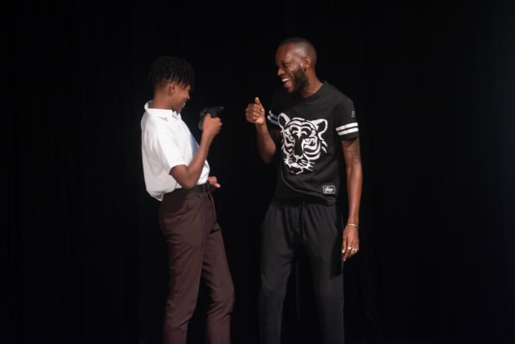 Drama coach Omari Asson with a student of the Asja Boys' College, San Fernando during the opening performance. - 