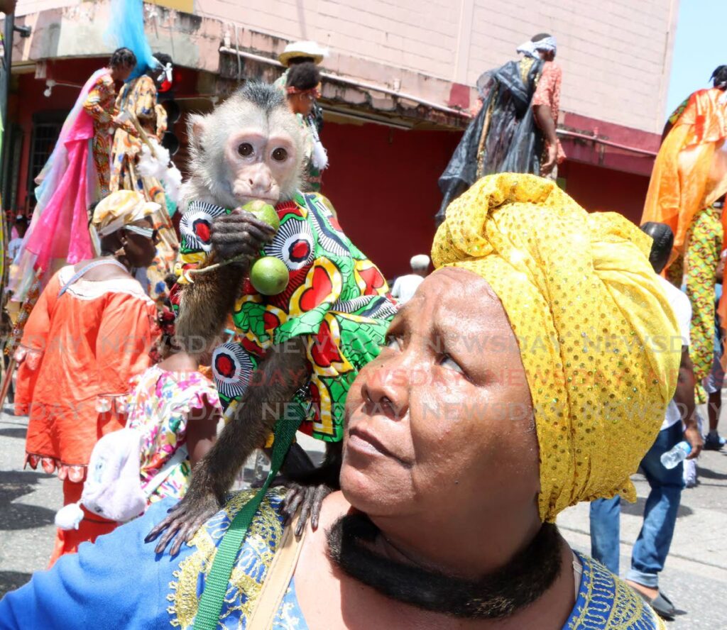 NO MONKEY BUSINESS: Dressed in Emancipation wear like his owner, a monkey enjoys some chennette during the Emancipation procession through Port of Spain on Tuesday.  - Photo by Angelo Marcelle