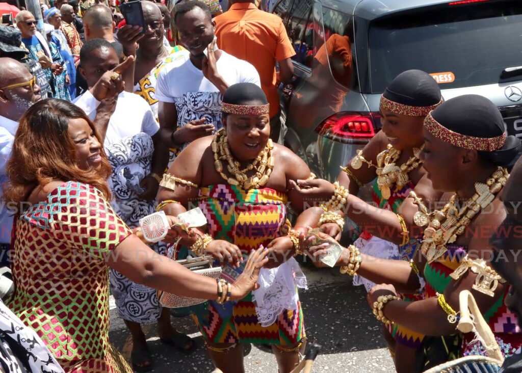 MAKING IT RAIN: The woman on the left gives money to show her appreciation to the Ghanaian dancers, during the  Emancipation procession through Port of Spain in 2023. - Photo by Angelo Marcelle