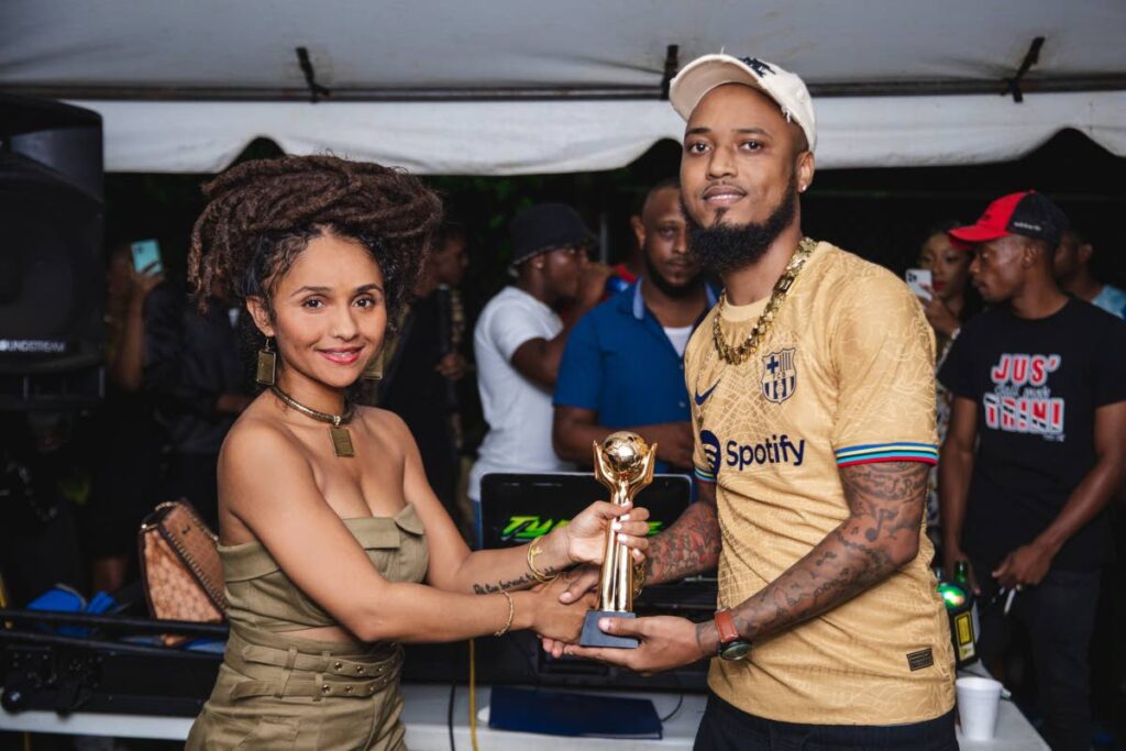 Kaya Ises, left, presents TT singer/music producer KG (Khalif Greaves) with the AEAUSA 2020 Best Upcoming Artist award, last June at his Reality Entertainment studio, Charles Street, Arima. - 