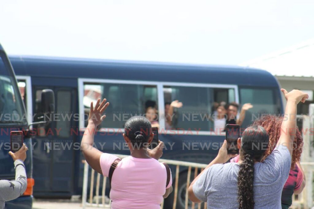 Relatives wave as a Coast Guard bus carries Venezuelan migrants from the heliport in Chaguaramas to Staubles Bay to be deported to Venezuela on Saturday morning. - Photo by Grevic Alvarado