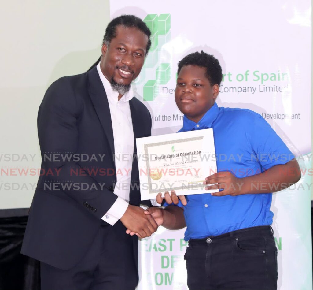 Minister in the Ministry of Housing and Urban Development Adrian Leonce presents Khalan Beard Cordner with his certificate of completion in the Youth Entrepreneurial Programme at the Russell Latapy Secondary School on Wednesday. - Angelo Marcelle