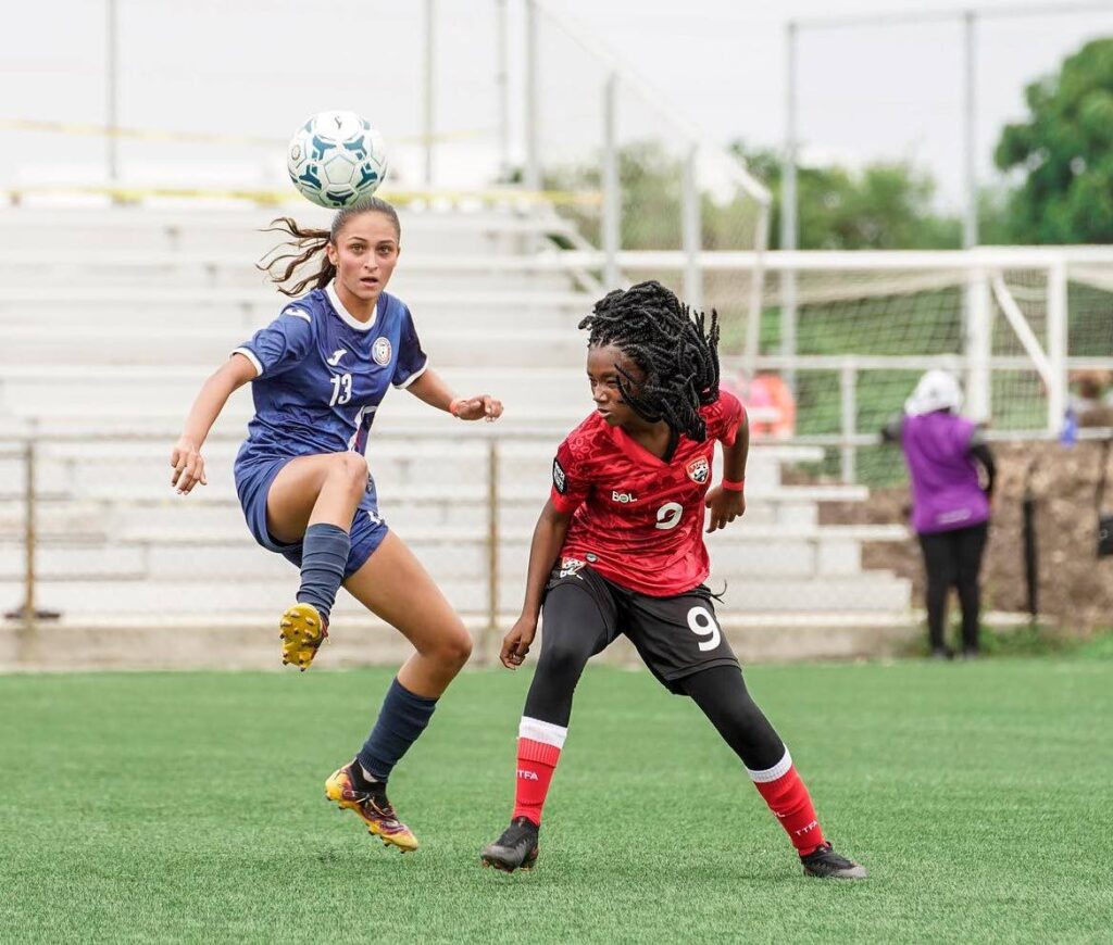 A Puerto Rican player, left, and her Trinidad and Tobago rival vie for the ball in a CFU Girls Under-14 Challenge match in Antigua.  - TTFA