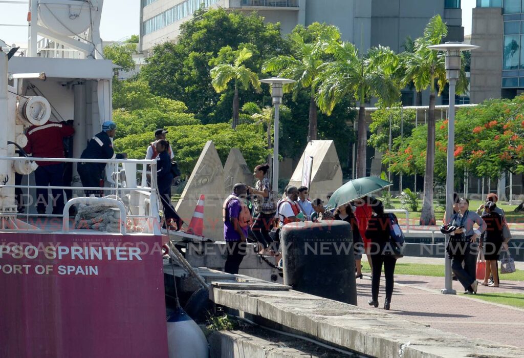 Crew members of the Calypso Sprinter water taxi look on as passengers come onboard a short distance from where Amrit Doogah, 34, died by suicide at the Port of Spain Waterfront on Monday. - Anisto Alves