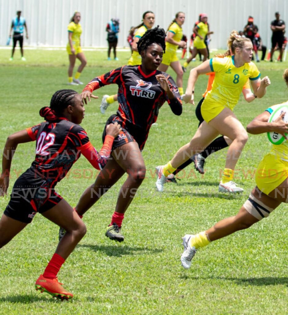 An Australian sprints away from Trinidad and Tobago  players during a women's rugby match at the Commonwealth Youth Games, Shaw Park Recreation Ground, Tobago, Sunday. Australia won 71-0 