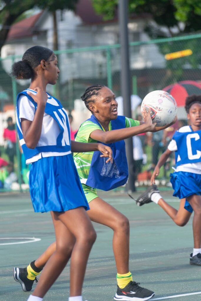Hill Girls wing attack Vanessa Lewis gets the ball through the swarm of Cardinals defenders in a Republic Bank Laventille Netball League beginners encounter at the Lystra Lewis Netball Courts, Nelson Mandela Park recently.