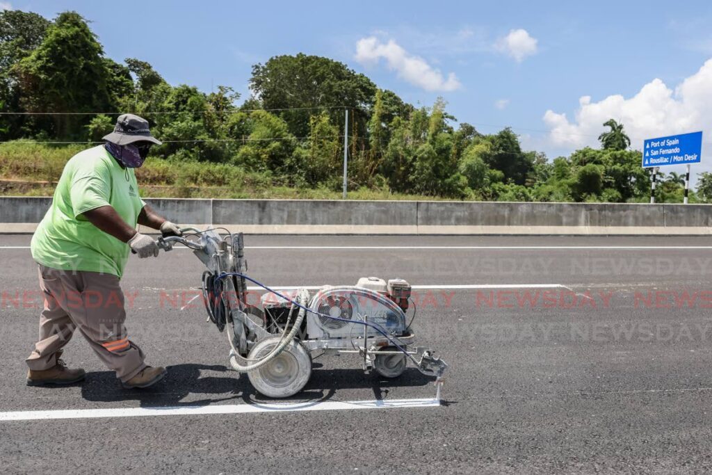Leon Richards sprays the white lines on a portion of the San Fernando to Point Fortin Highway near the La Brea Interchange on Sunday in preparation for the opening of that section of the highway to the public on Monday.