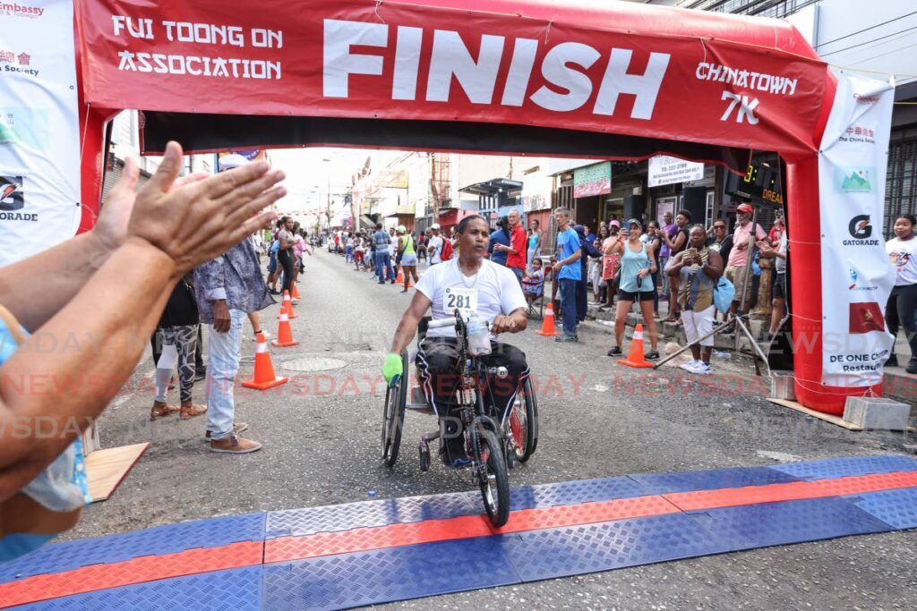 Gerard Asyn franchit la ligne d'arrivée en fauteuil roulant au Chinatown 7K dimanche.