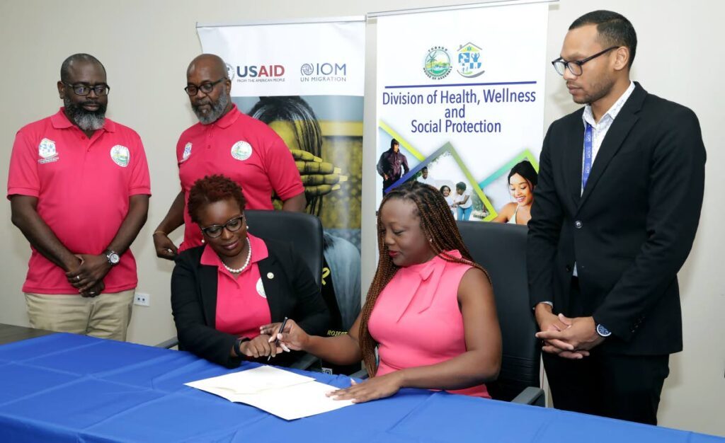 DHWSP's Dr Faith B Yisrael, seated at left, prepares to sign for receiving the donation of 15 laptops  from IOM-TT' head of office Jewel Ali.  - 