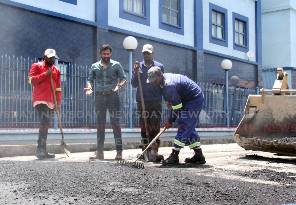 Minister in the Ministry of Works and Transport Richie Sookhai, second from left, looks on as employees of Jusamco Pavers Ltd work on Richmond Street, Port of Spain, as part of the ministry's road-rehabilitation programme on Sunday. - Ayanna Kinsale