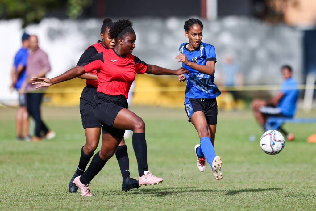 Holy Name Convent attacker Chaya Vincent, right, takes a shot while under pressure from Bishop Anstey High defenders during a Secondary School Football League girls north zone championship match at the St Mary's College grounds, St Clair on Thursday.  - Photo by Daniel Prentice