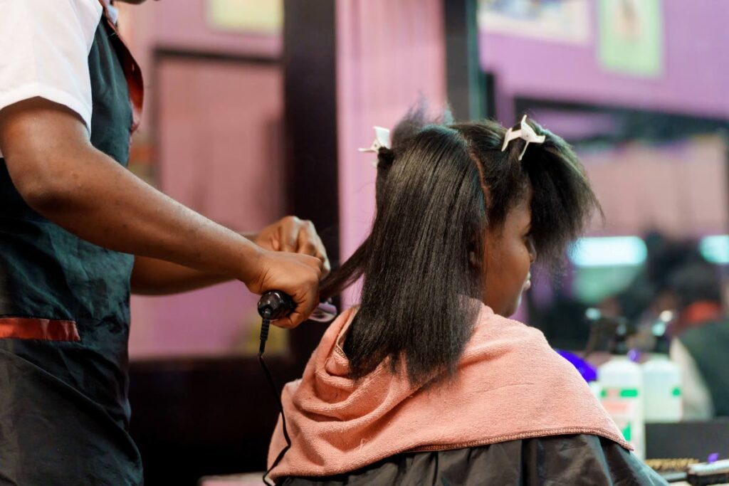 A trainee in the National Centre for Persons with Disabilities beauty culture programme styles this woman's hair during a training session. - Photo by Scotiabank