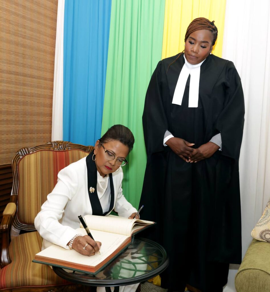 President Christine Kangaloo signs the visitors' book at the Tobago House of Assembly as presiding officer Abby Taylor looks on Wednesday. - Photo courtesy THA
