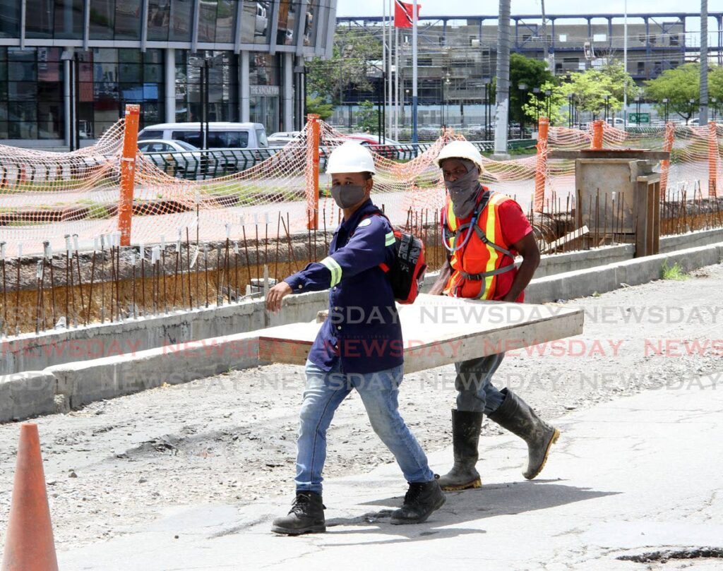 Construction workers carry a piece of board along Lady Hailes Avenue, San Fernando in 2021. In Monday’s budget, Finance Minister said contractors owed by the State will be paid with a $1.5 billion loan. - FILE PHOTO 