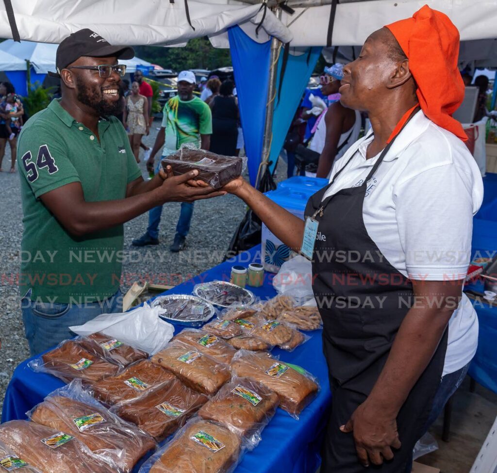 FLASHBACK: Bon Accord resident Phil Williams, left, buys a black cake made from dasheen from vendor Susan Harnandez at Blue Food Festival 2022.  - FILE PHOTO 