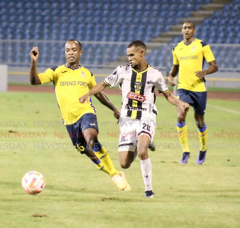 Moca FC's Carlos Rossell, right, is defended by Defence Force's Kevon Goddard on Wednesday. - Photo by Grevic Alvarado