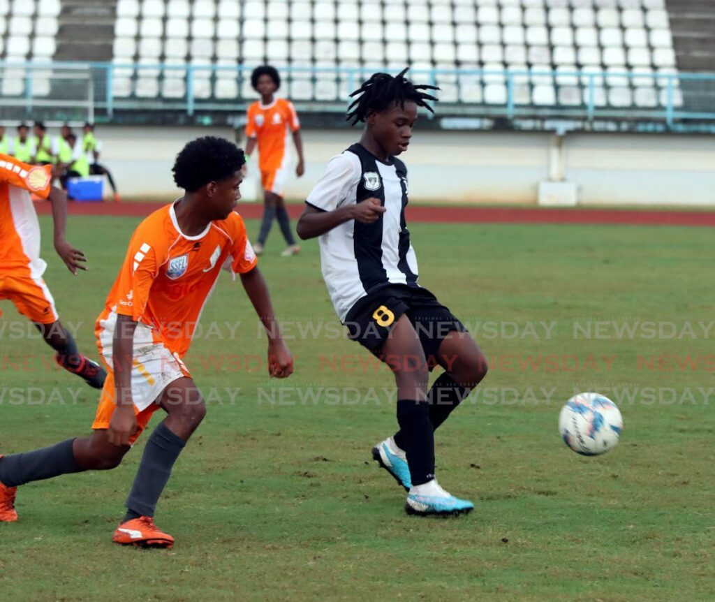Kalif Sylvester of Holy Cross College makes a pass while tracked by Khaleel Campbell of Valencia Secondary, during their SSFL Championship Division game, at the Larry Gomes Stadium, Arima on Friday.  - 