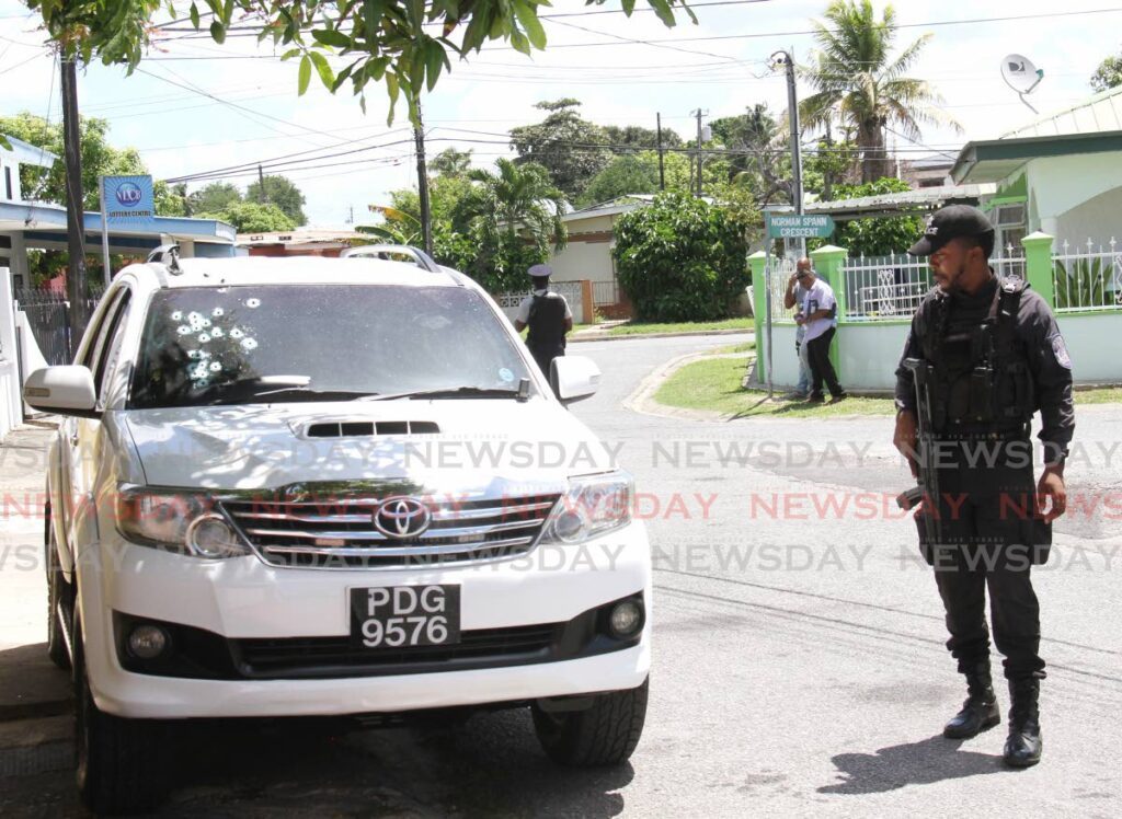 A police officer takes a closer look at the bullet holes in the windcreen of a SUV outside the deputy commissioner of prisons home in Barataria on October 11.  - File photo/Ayanna Kinsale