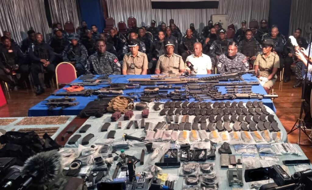 Police Commissioner Erla Harewood Christopher, third from left, Snr Supt Roger Alexander, second from right, task force heads, and members of the Inter-Agency Task Force and the Guard and Emergency Branch with a large quantity of arms and ammunition seized in Santa Cruz. PHOTO COURTESY TTPS - 