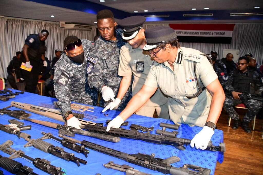 Police Commissioner Erla Harewood-Christopher, right, and other police officials examine weapons found and siezed earlier that day during an exercise in Santa Cruz TTPS PHOTO - 
