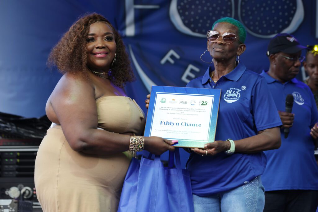 Assistant secretary in the Division of Tourism, Culture, Antiquities and Transportation, Assemblyman Megan Morrison, presents a plaque to Ethlyn Chance during the Tobago Blue Food Festival at the Bloody Bay Recreation Ground on Sunday. PHOTO COURTESY THA