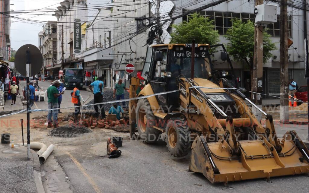WASA workmen make repairs to a massive water leak at the intersection of Queen Street and Frederick Street in Port of Spain, on Tuesday. - Photo by Roger Jacob
