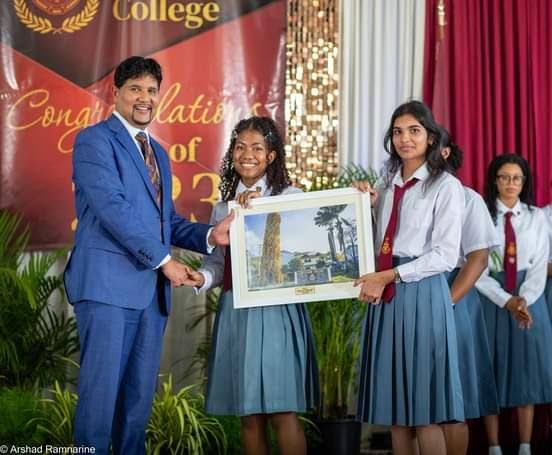 Justice Frank Seepersad receives a painting of Hillview College, El Dorado, from two students at the school's graduation ceremony last week. - Photo courtesy Hillview College photography club