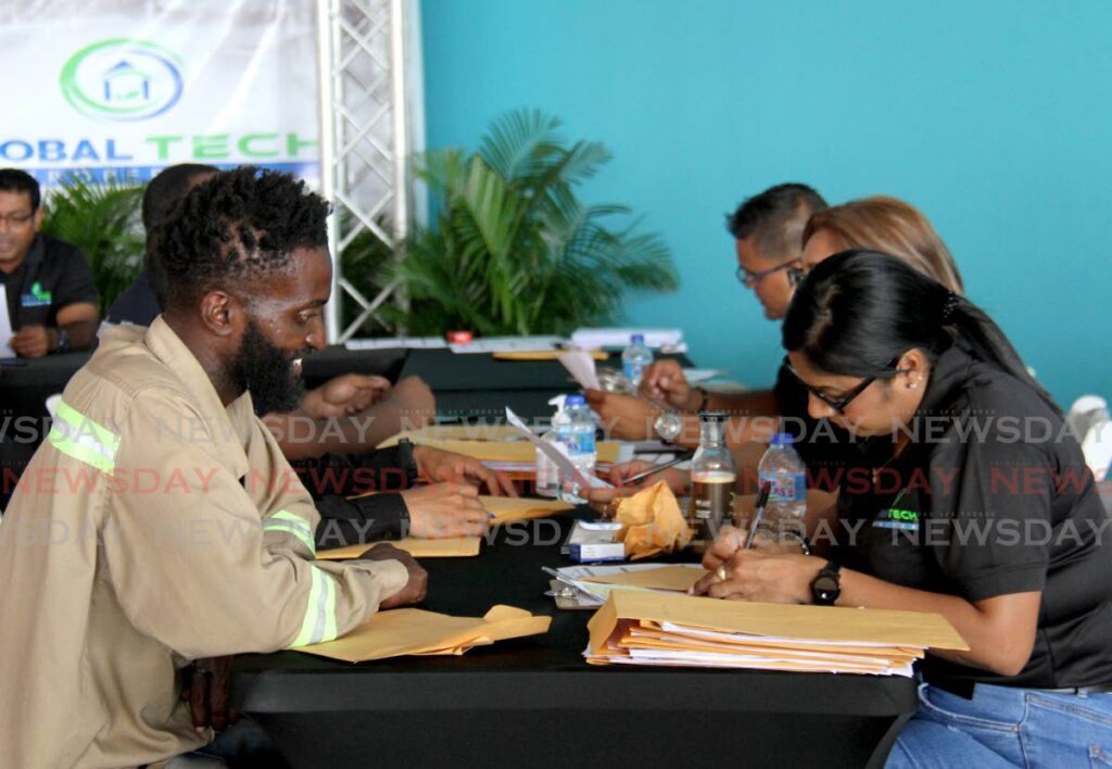 Global Tech officials assist applicants fill out forms during their job fair at C3 Centre, San Fernando. The fair is geared towards individuals seeking employment in the Guyana market.  - AYANNA KINSALE