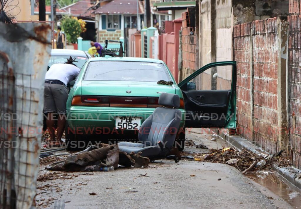 A Belmont resident cleans his car after it was damaged by floodwater on Sunday. - Angelo Marcelle