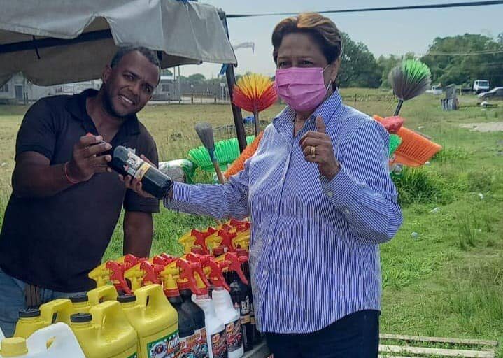 Opposition Leader Kamla Persad-Bissessar with a vendor on her return from overseas on Monday. Photo: Kamla Persad-Bissessar Facebook page. - 