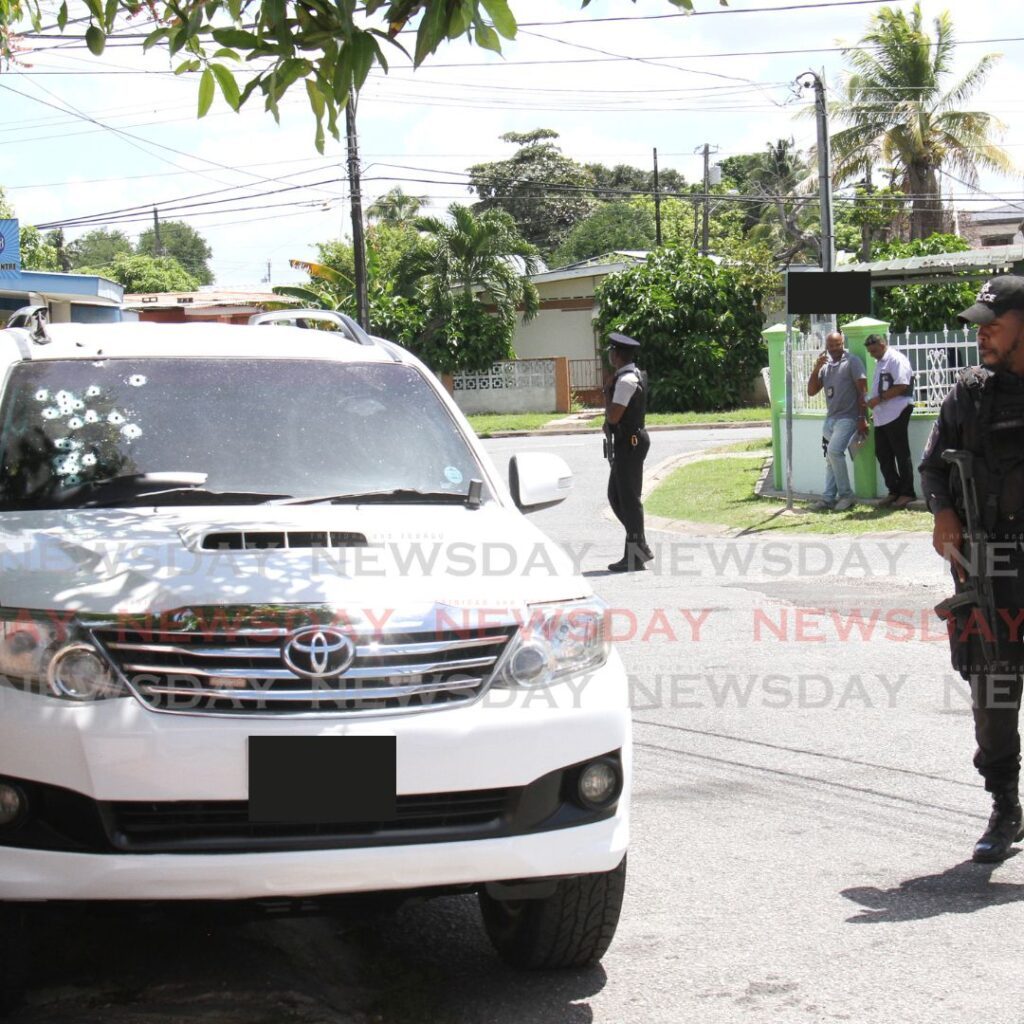 In this October 11 file photo, an officer looks at the bullet riddled SUV outside the house of Deputy Prisons Commissioner Sherwin Bruce on Sparrow Avenue, Barataria. - Photo by Ayanna Kinsale