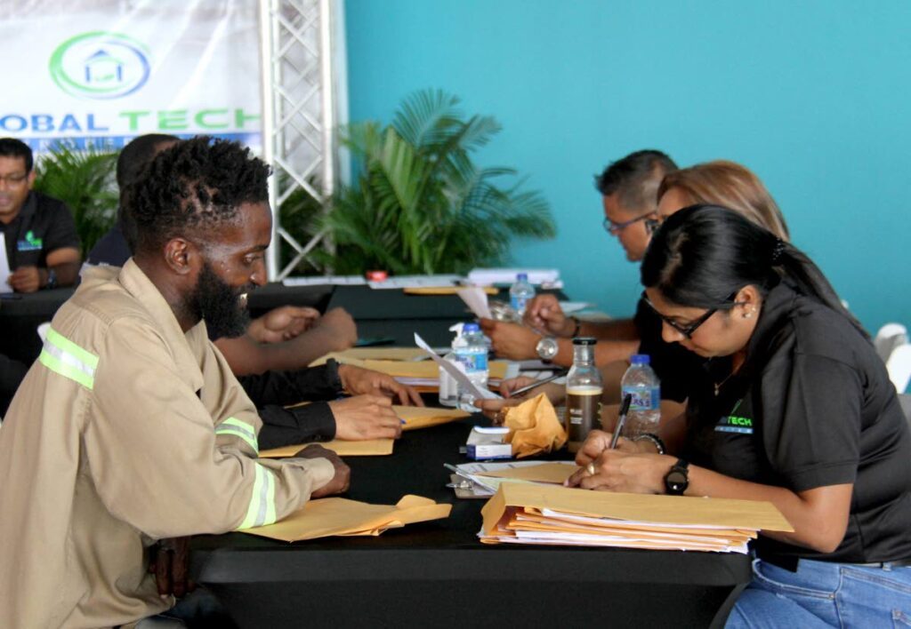Global Tech officials assist applicants fill out forms during their job fair at C3 Centre, San Fernando. The fair is geared towards individuals seeking employment in the Guyana market - AYANNA KINSALE