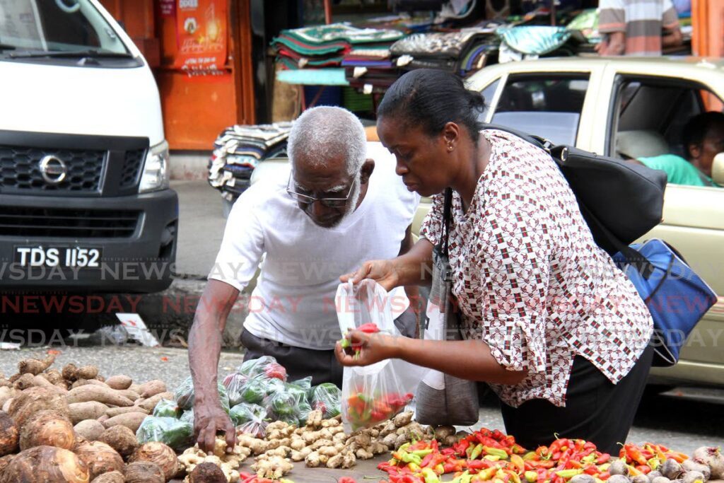 Customers buy locally grown produce from a vendor at Charlotte Street, Port of Spain.  - Ayanna Kinsale