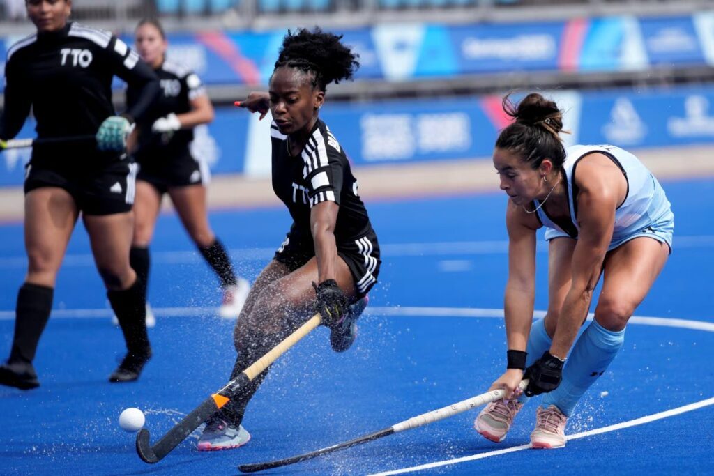 Argentina’s Delfina Thome (R) and TT’s Kayla Brathwaite (C) battle for the ball during a women’s field hockey match at the Pan American Games in Santiago, Chile, on Monday. - AP PHOTO
