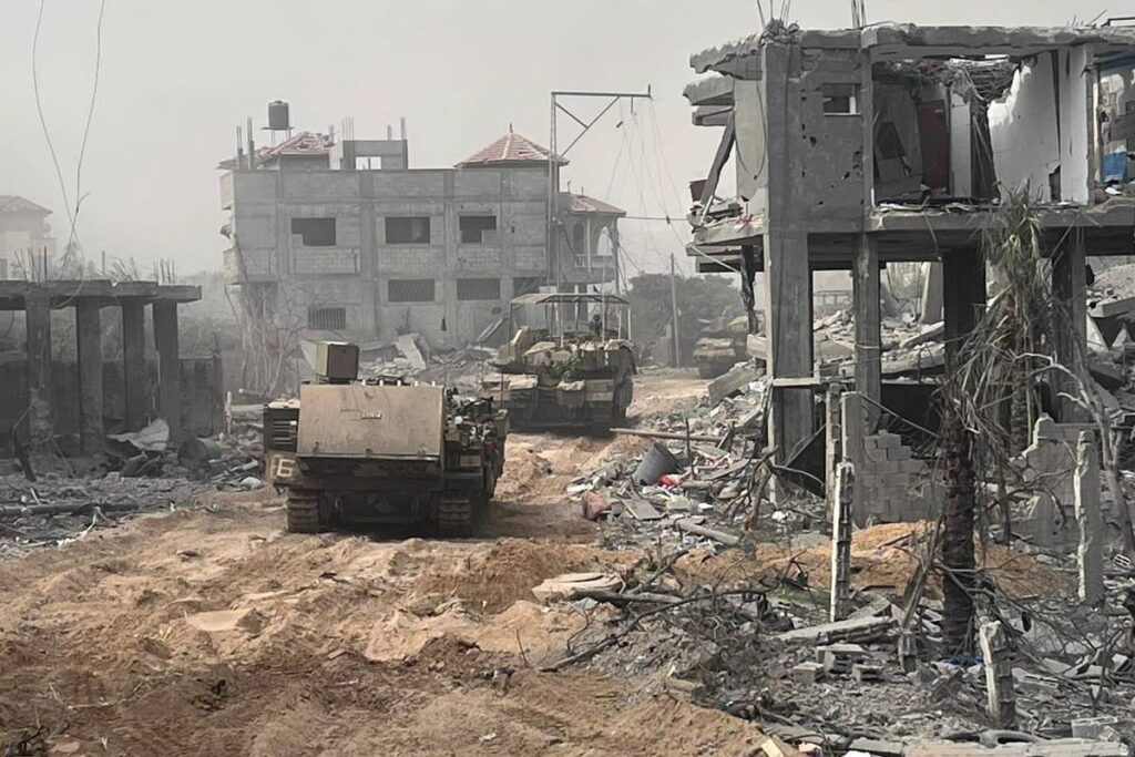 In this undated photo provided by the Israeli military, Israeli armoured personnel carriers move past destroyed buildings during a ground operation in the Gaza Strip. Israel Defence Forces via AP - 