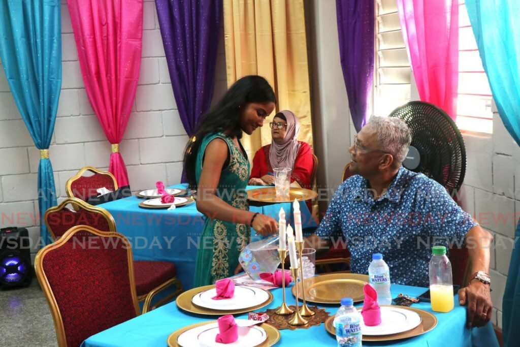 Form five student Leanne Sayneeram serves Cunupia Secondary School former principal Dennis Lalla a meal from the Masala Hut at the school's restaurant competition. - Joey Bartlett