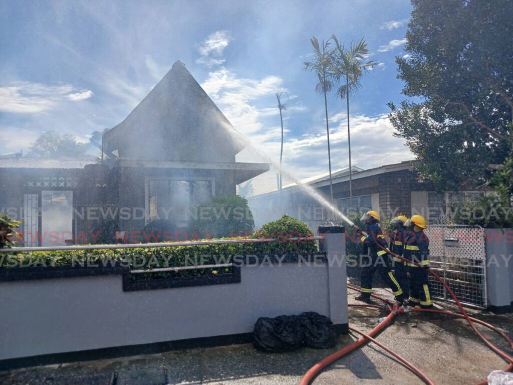 Officers of the Wrightson Road Fire Station extinguishing a fire at a home on Carlos Street, Woodbrook on Friday morning. - Photo by Joey Bartlett