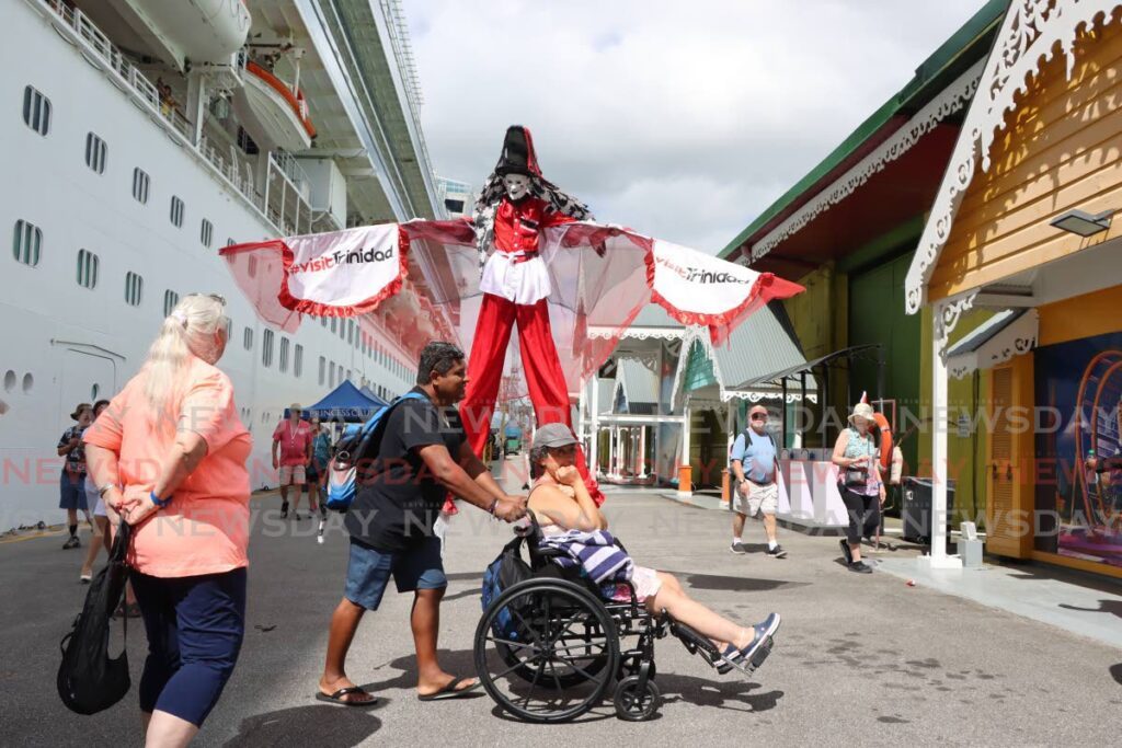 A moko jumbie towers over tourists who disembarked from the Ruby Princess cruise ship at the Cruise Ship Complex, Dock Road, Port of Spain on Tuesday. PHOTO BY ANGELO MARCELLE - Angelo Marcelle