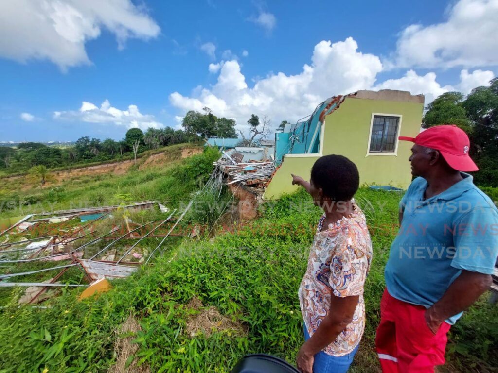 Belle Vue residents Marva Fitz and Allan Miller look at the  collapsed houses destroyed by a landslide caused by quarrying in the area. - Photo by Lincoln Holder