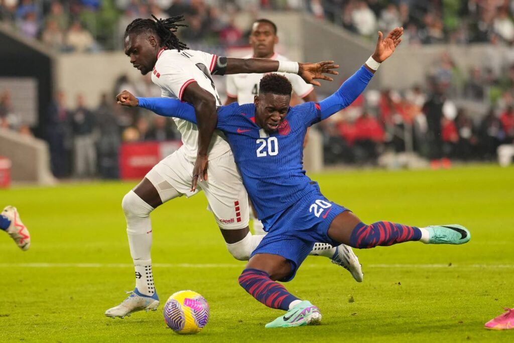 Folarin Balogun of the United States goes down under pressure from TT’s Aubrey David (L) during the second half of a Concacaf Nations League Quarterfinal Round leg 1 match at Q2 Stadium on Thursday in Austin, Texas.  - 