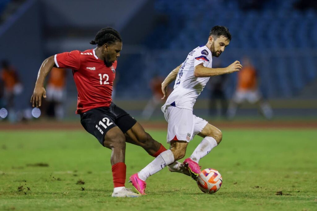 TT’s Daniel Phillips (L) defends against the US during the second-leg Nations League quarter-final match, at the Hasely Crawford Stadium, Port of Spain, on Monday. TT won the match 2-1 but lost 4-2 on aggregate. - DANIEL PRENTICE