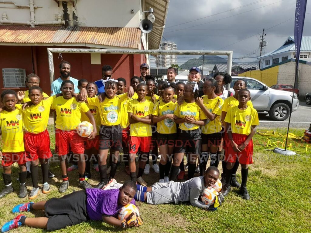 Members of the St Crispin's Anglican Primary School football team with technical staff of the US men's football team who made a donation of equipment at the school's compound on Ariapita Avenue in Woodbrook on Tuesday.  - Roneil Walcott