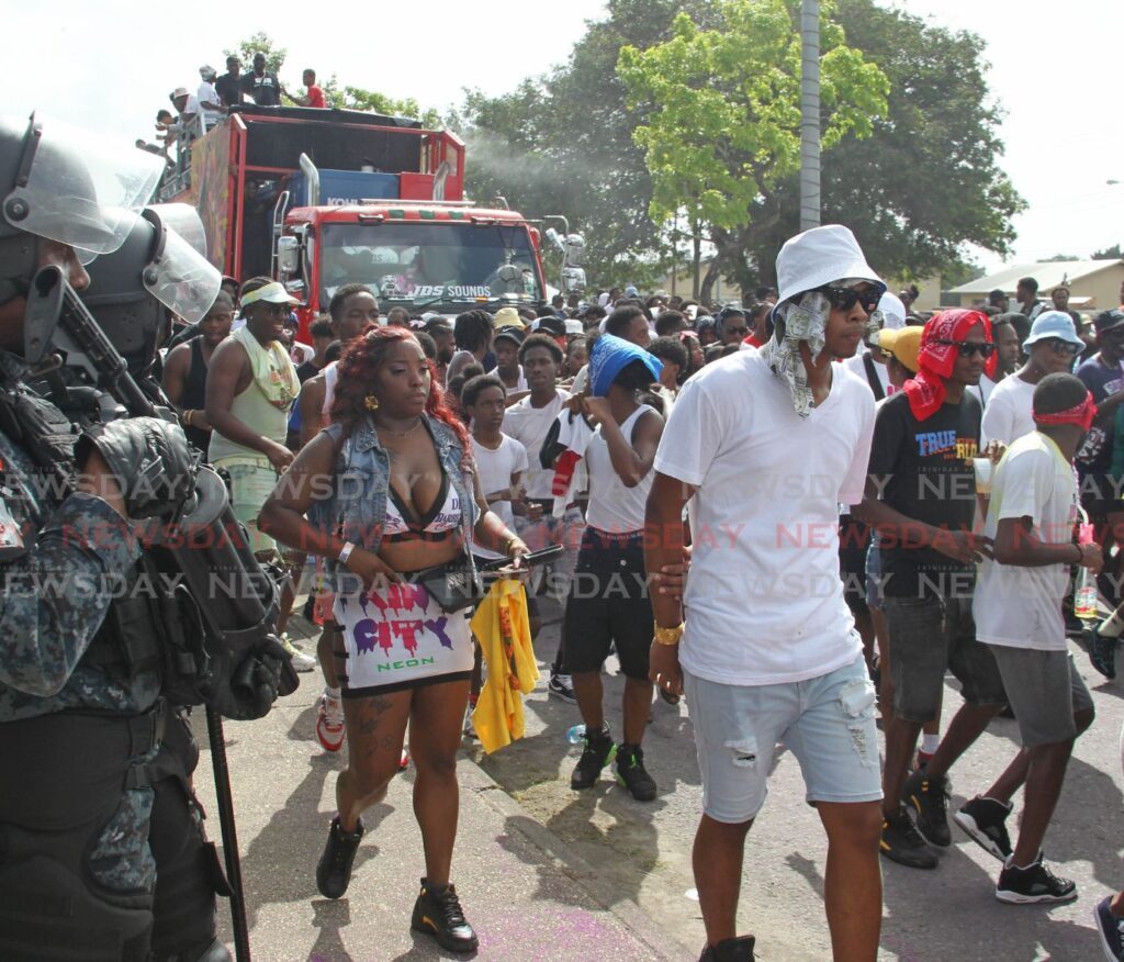 Police officers keep a watchful eye on celebrants in the J'ouvert  celebrations along the Rienzi Kirton Highway in San Fernando all part of San Fernando City Month. - Photo by Lincoln Holder