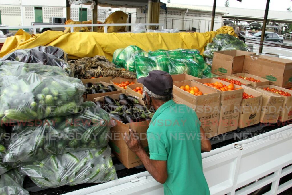 A farmer packs his produce on the tray of a truck at the Namdevco Farmers Market in Debe. - File photo by Ayanna Kinsale