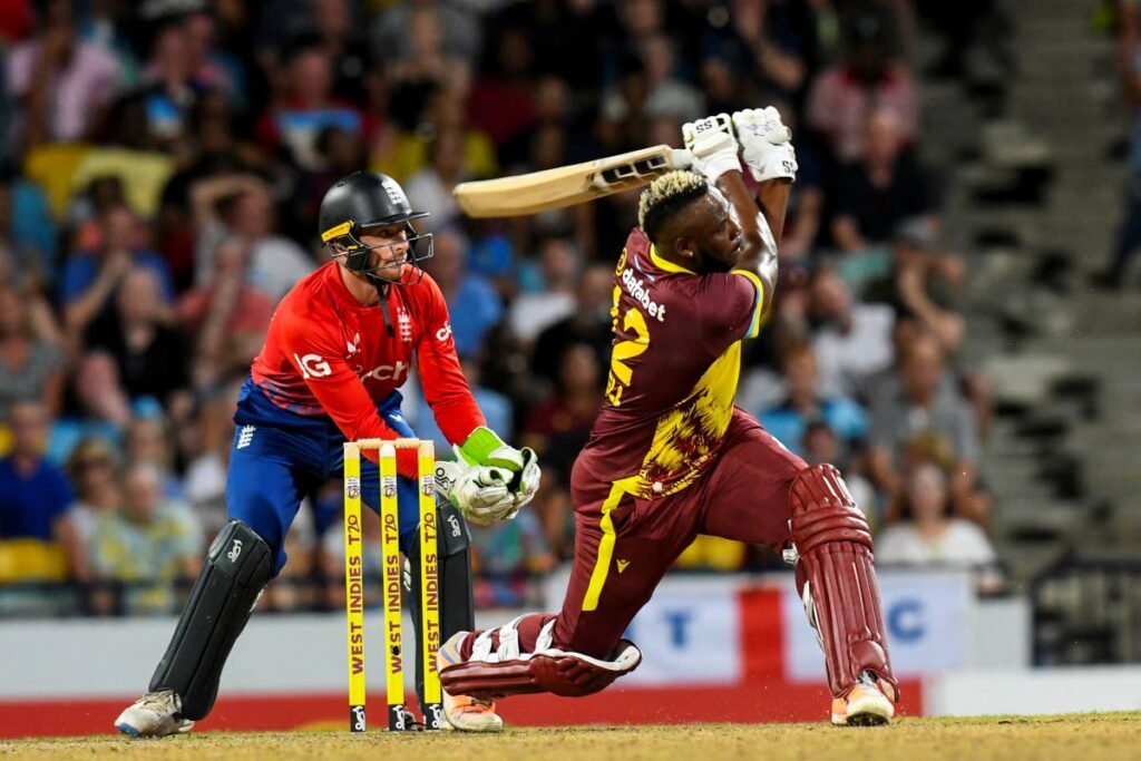 West Indies' Andre Russell hits a six as Jos Buttler of England watches during the 1st T20I at Kensington Oval, Bridgetown, Barbados, on Tuesday.  - AFP PHOTO