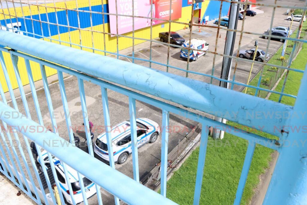 Police and an ambulance at the scene of a police-involved shooting in which siblings Simeon and Sinaaya Lessey were killed and three others wounded at Courts Megastore, Barataria on Sunday. - Photo by Angelo Marcelle