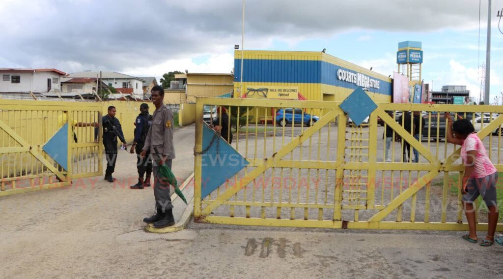 A relative, right, weeps at the entrance to the Courts Megastore in Aranguez, after learning that siblings Sinaya and Simeon Lessey had been shot and killed, while two other relatives had been wounded in a shooting at the store on Sunday. The wounded were taken to hospital. - Photo by Angelo Marcelle